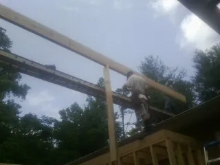 Carpenter setting a ridge beam over a new addition frame — Ice Dam Removal by Roofing Brothers in Hicksville