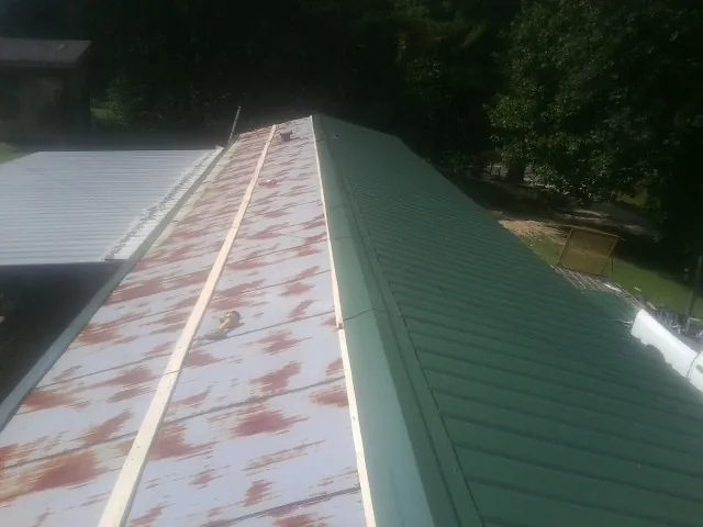 Old rusted panels beside newly installed green metal roofing — Wind Damage Roof Repair by Roofing Brothers in Hicksville