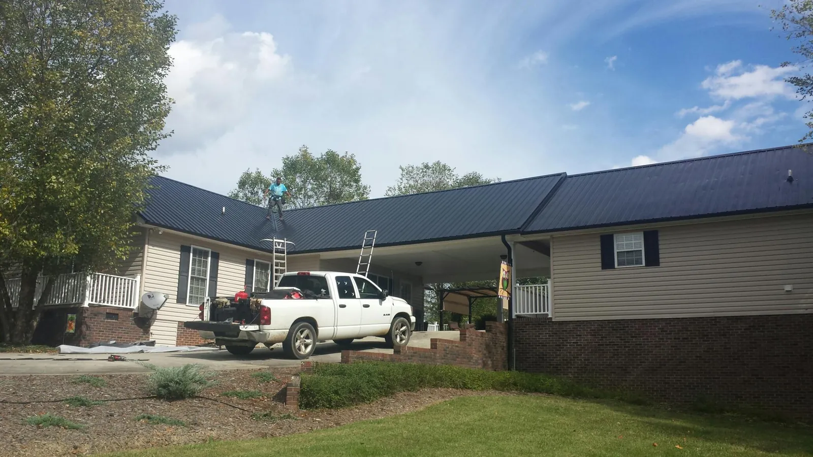 Black metal roof over a home and attached breezeway with ladders set in Hicksville