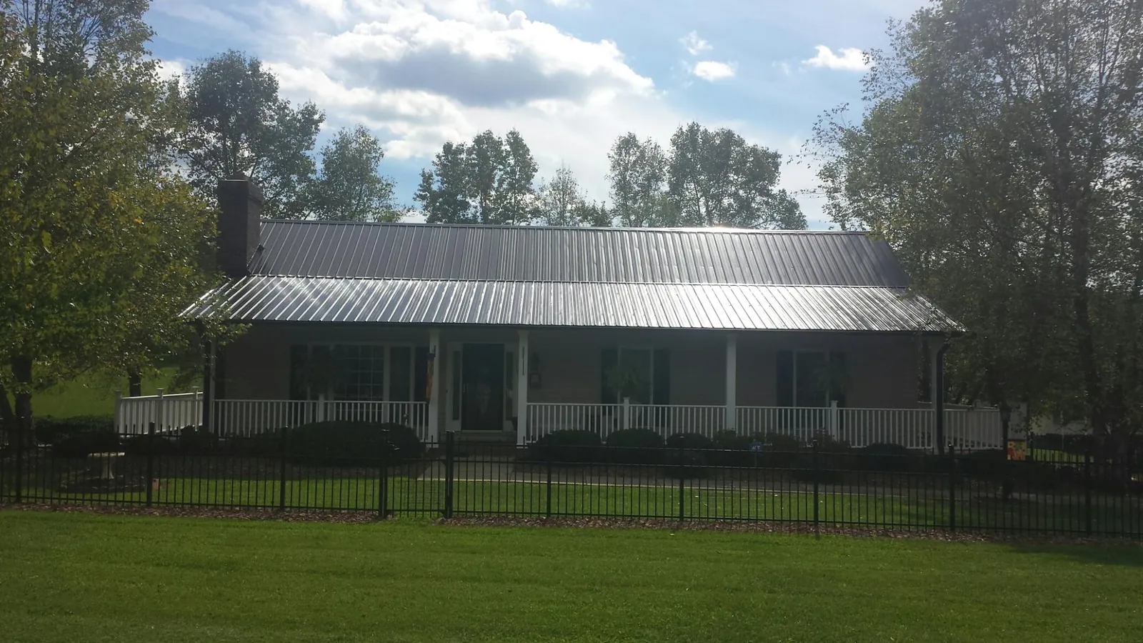 Gray metal roof on a brick ranch with a full width front porch — Gutter Guard Installation work by our crew in Hicksville