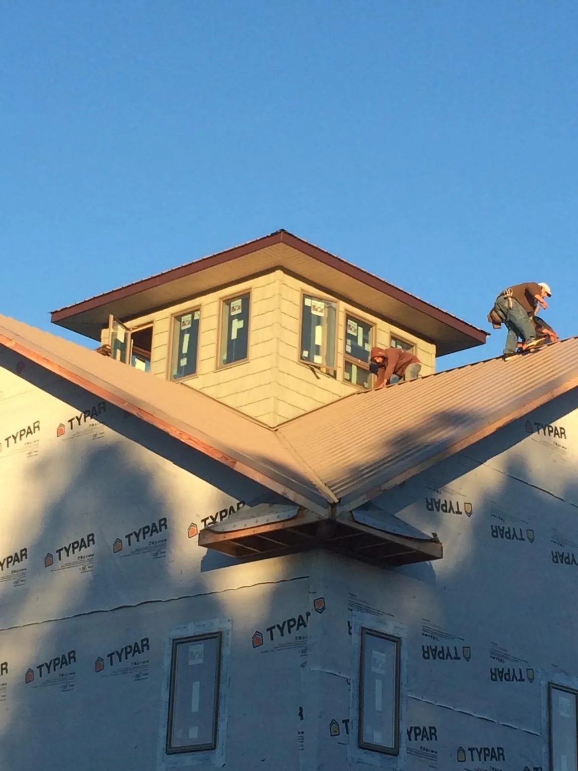 Roofers working around a rooftop cupola on a new metal roof at sunset — Roof Waterproofing in Hicksville by Roofing Brothers